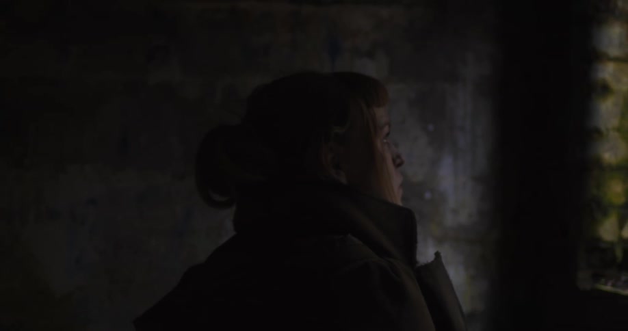 A woman walking in an old building then looking out the window