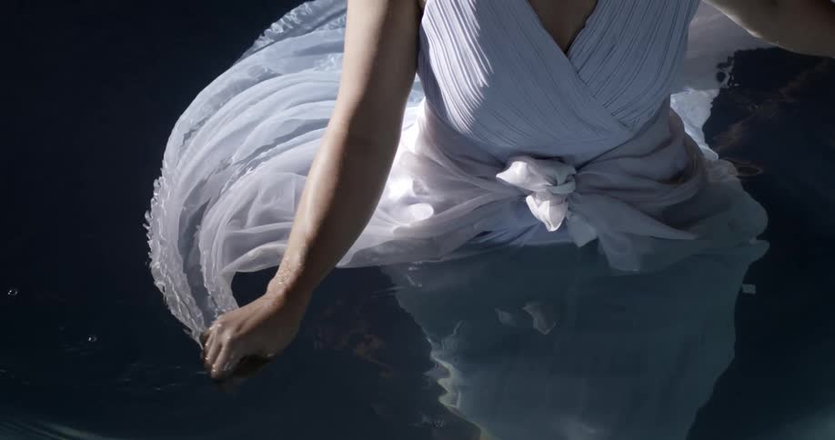 A woman in a dress stands in water