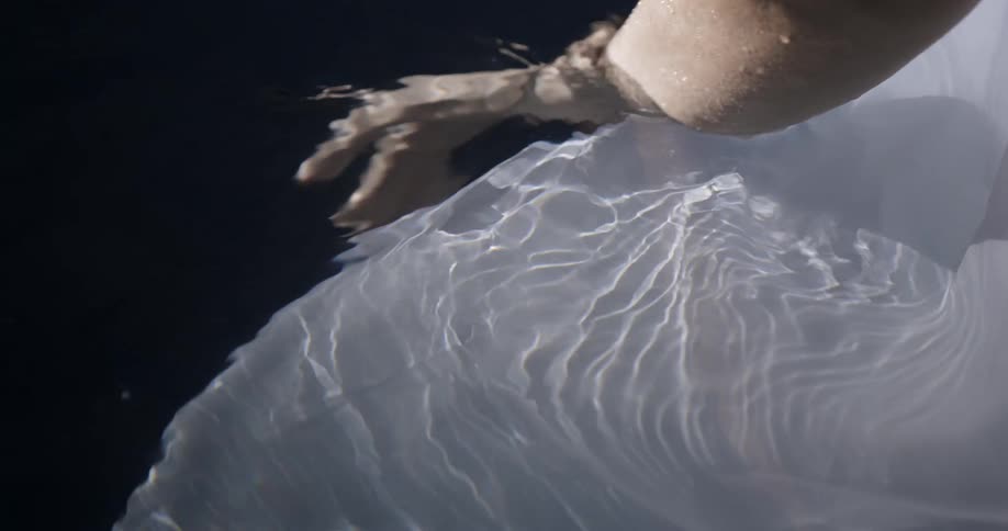 A woman in a white dress floats in water