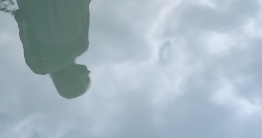 A reflection of a woman is displayed in water