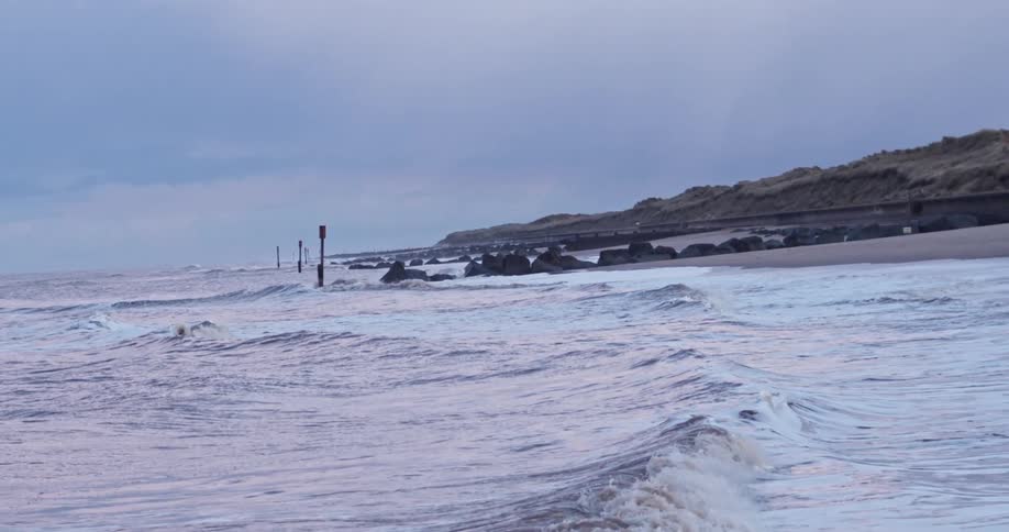 Ocean waves break against the shore at dusk