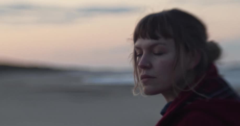 A woman sits on a beach and looks around