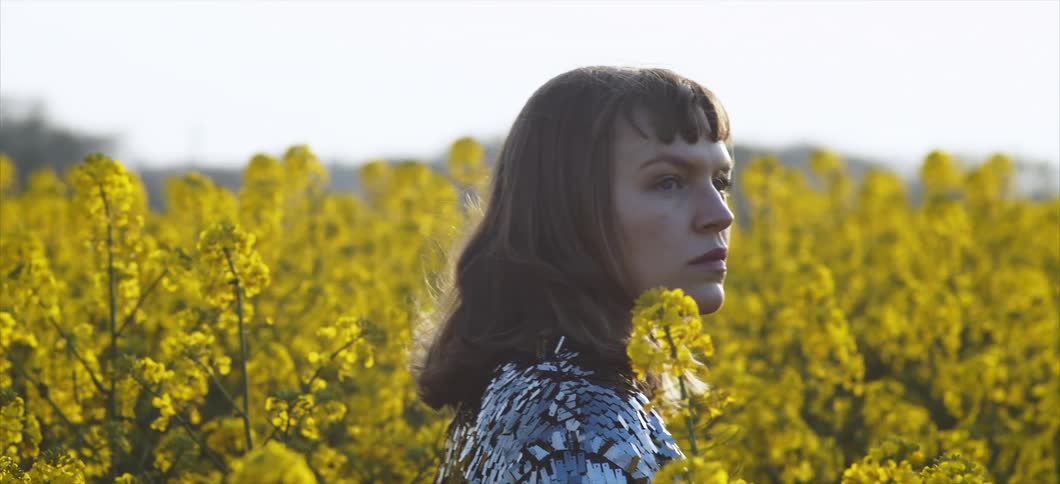 Unhappy woman in a field of yellow blossoms in the country on a breezy day