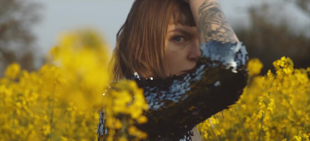 A woman stands in a field full of flowers