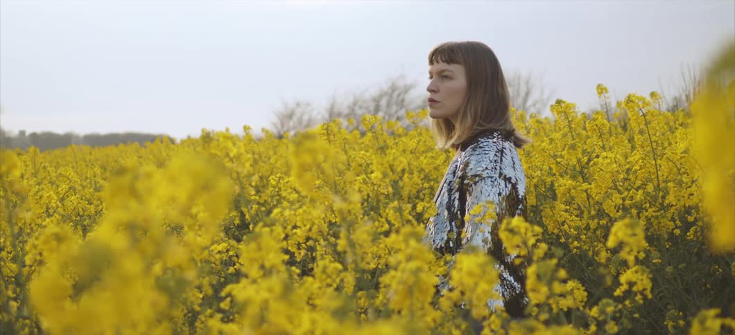 A woman walks through a field of flowers