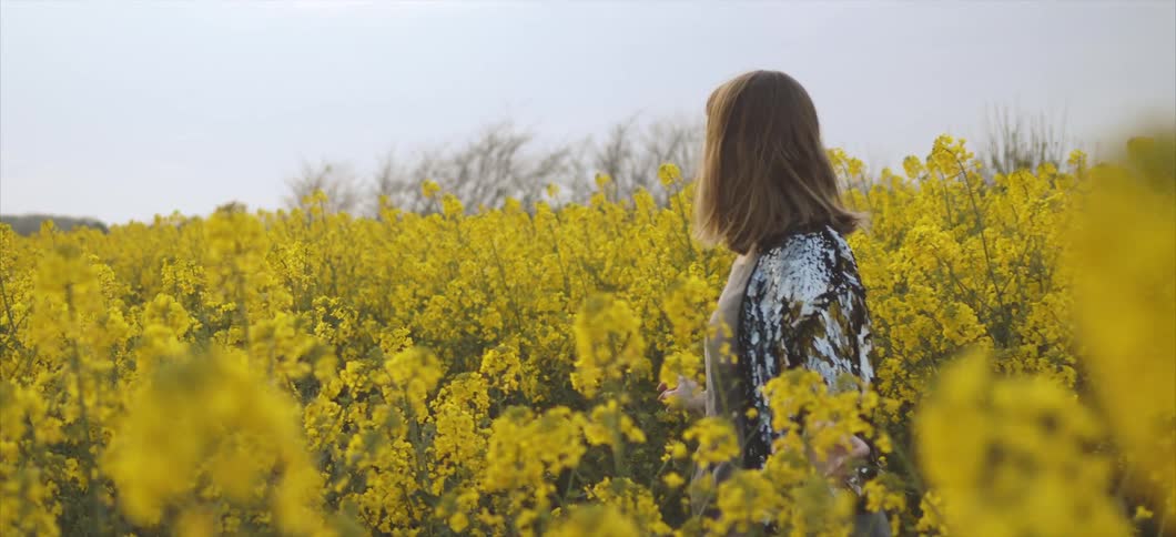A woman is walking through a field of flowers