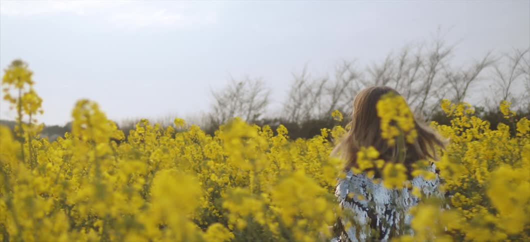 A young woman running through a field of flowers