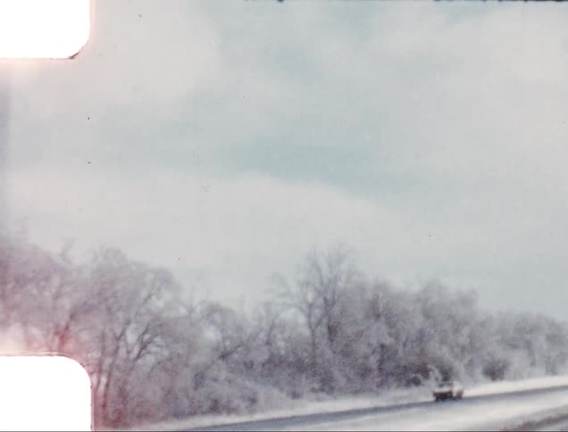 A lone car drives by on a snowy highway