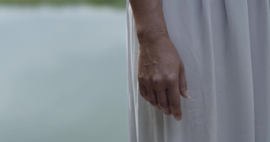 Woman in a white gown stands with her arm at her side
