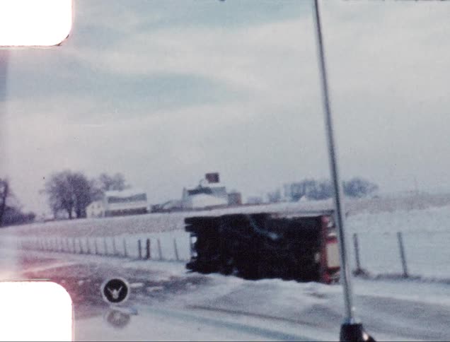 Vintage footage of a shipping truck overturned on the side of the road in the country