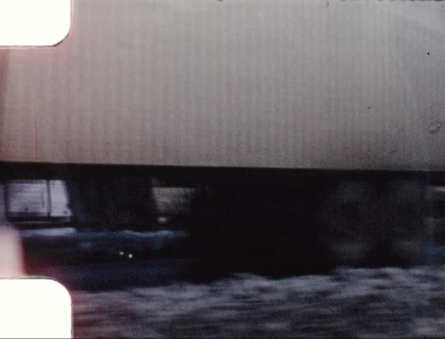 Traffic flows pass semi truck listing in ditch near slush on snowy day