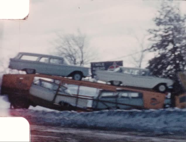Driving down plowed street past car hauler and snow covered ground