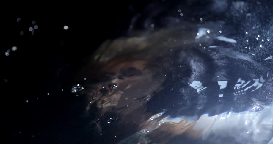 A white woman in a white dress floats underneath the surface of a body of water