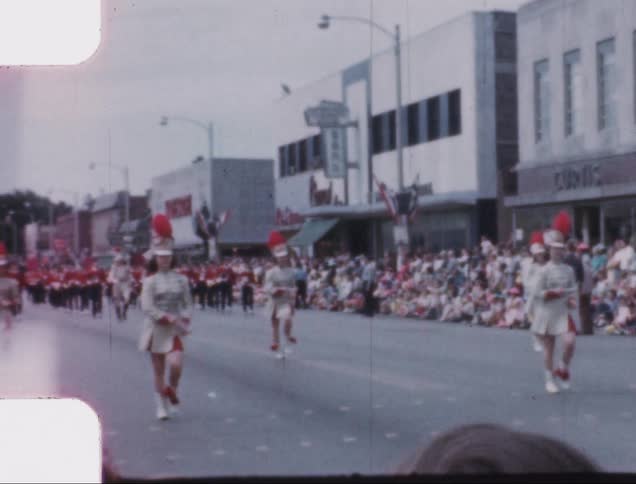 A group of women in uniform marching in uniform at the front of a parade down a city street