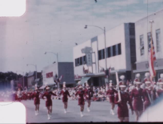 A parade passes onlookers on the main street of a small town