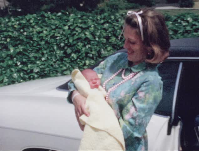 A woman coming out of a car holding a baby