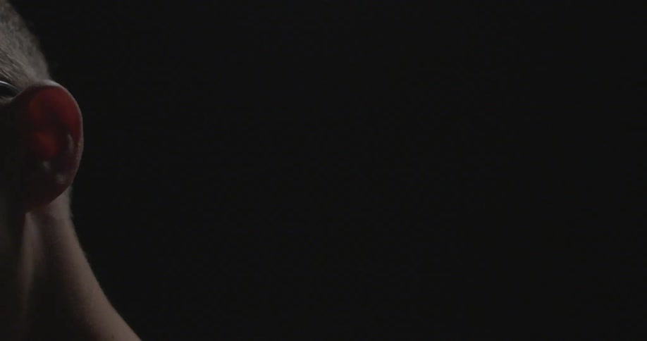 The side of a person's head can be seen in a dark area
