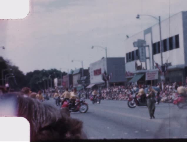 Vintage film of motorcycles on a parade in a small town street
