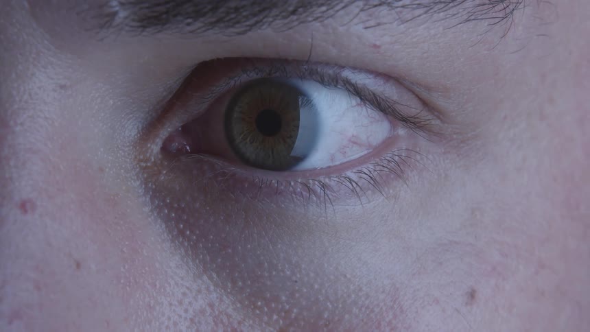 A person opens their eyelid and looks around