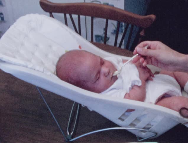 Mother feeds baby food to her baby with a spoon