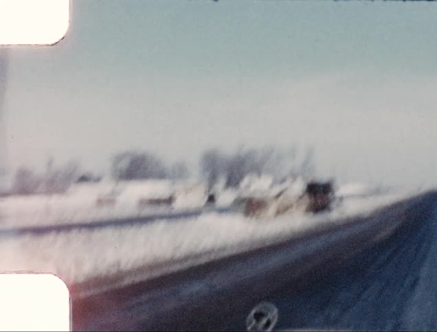 A car drives by a flipped over truck on the side of a freeway