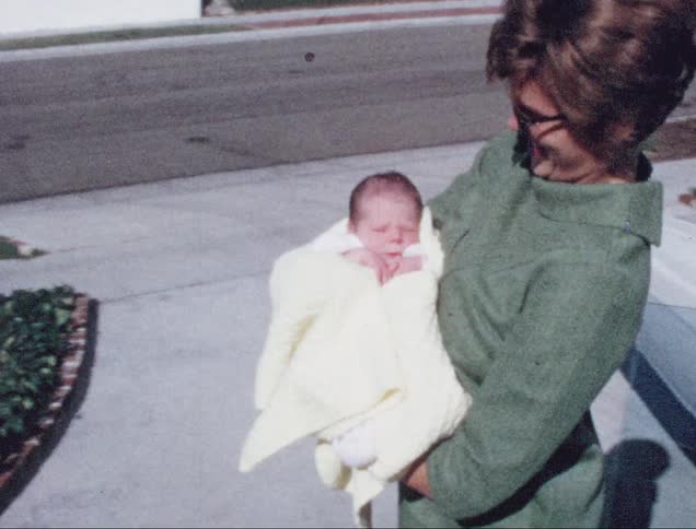 A mother is carrying her newborn outdoors
