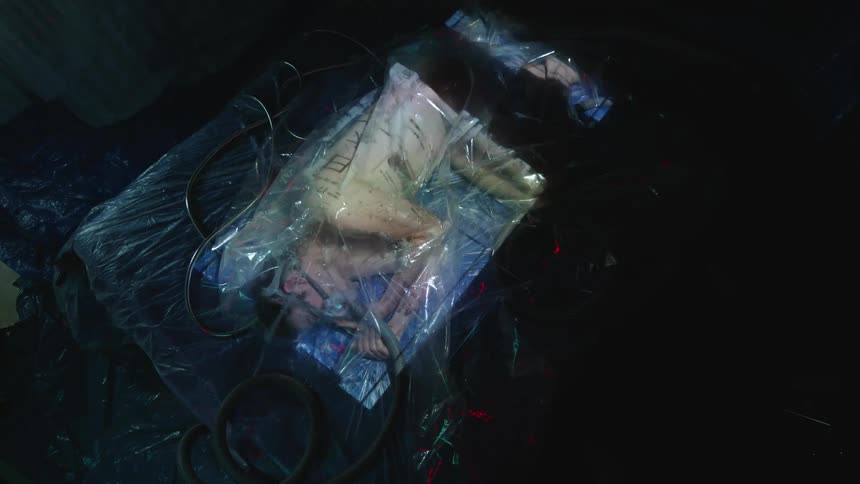 Colored lights flash over a bag containing a human being