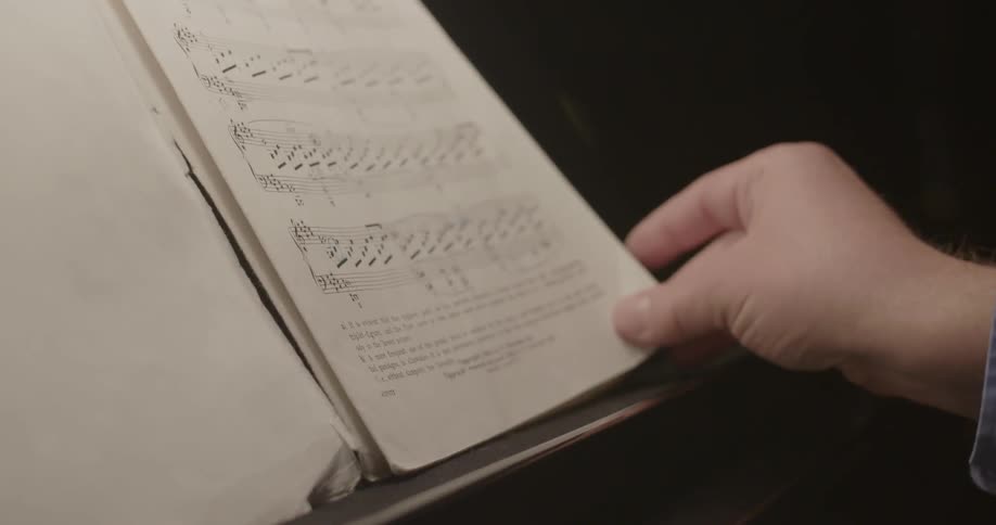 A person turns a music sheet on a stand