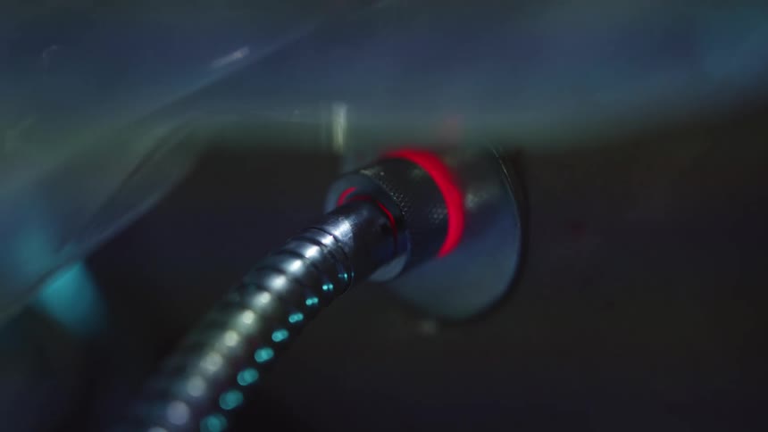 A cable with a pulsating light plugged into a white persons back