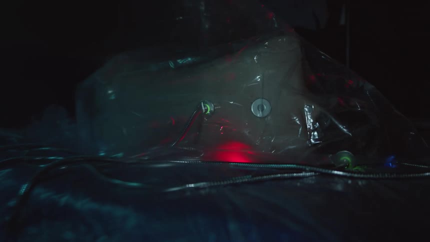 White substance containing plastic bag attached to cordleading to flashing lights in dark area