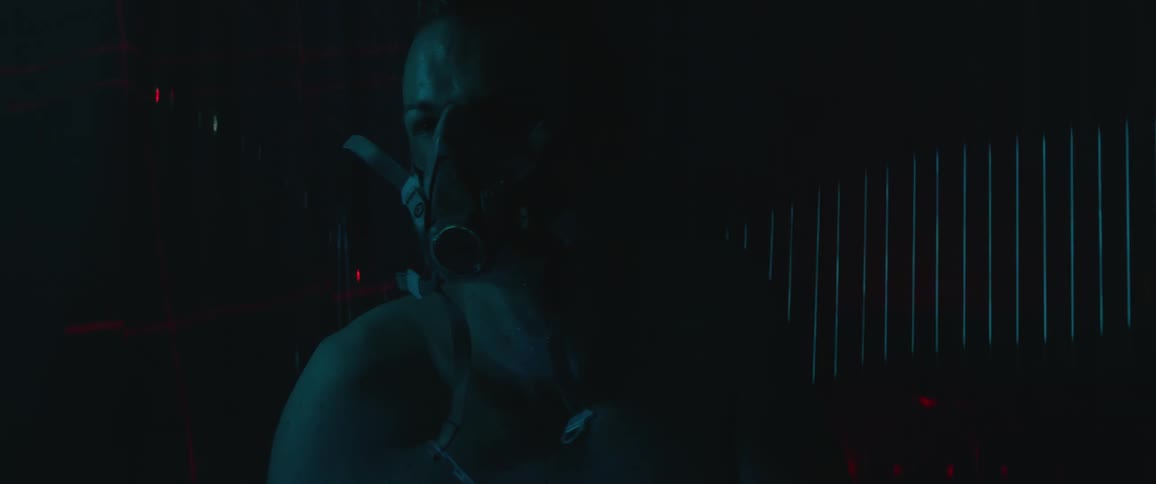 A man in a gas mask stands up in a dark room