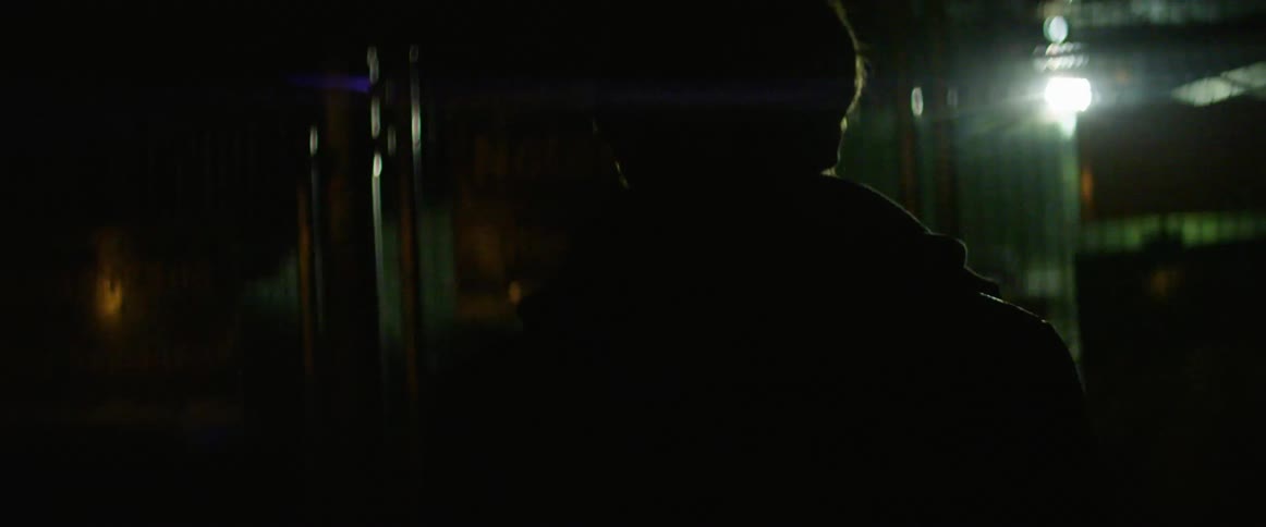 A man wearing a coat walks up to a metal barrier