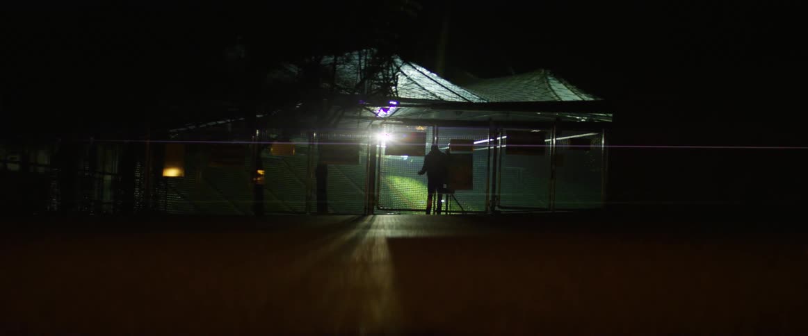 Man checks the gates of a stadium at night