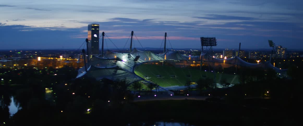 An empty sports stadium is lit up at night with visible netting above the seats