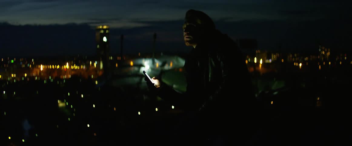 A white man uses a smartphone while standing outdoors in an urban area