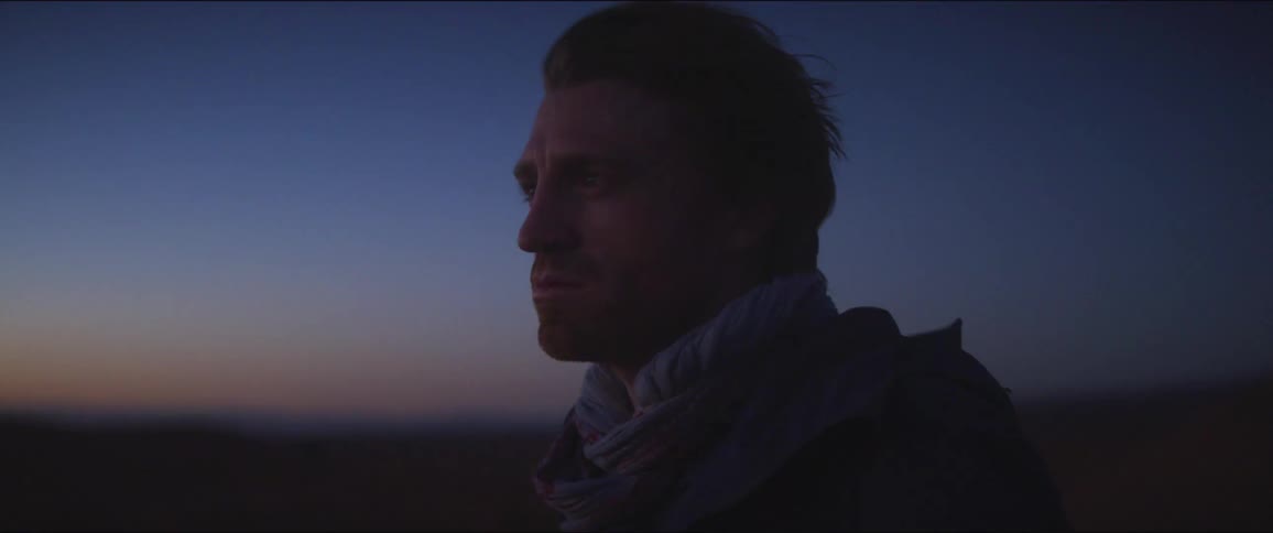 Man looks around in the field at dusk