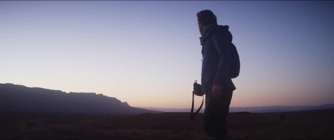 Man walks down the sand dune in the desert at dusk
