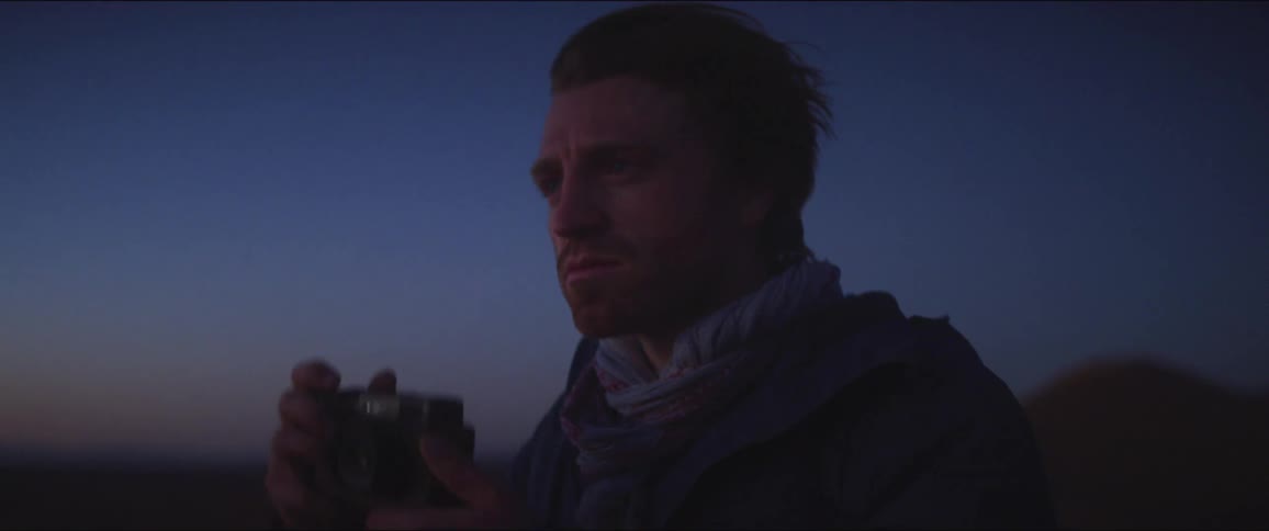 Man stands and take a picture with his camera in the desert