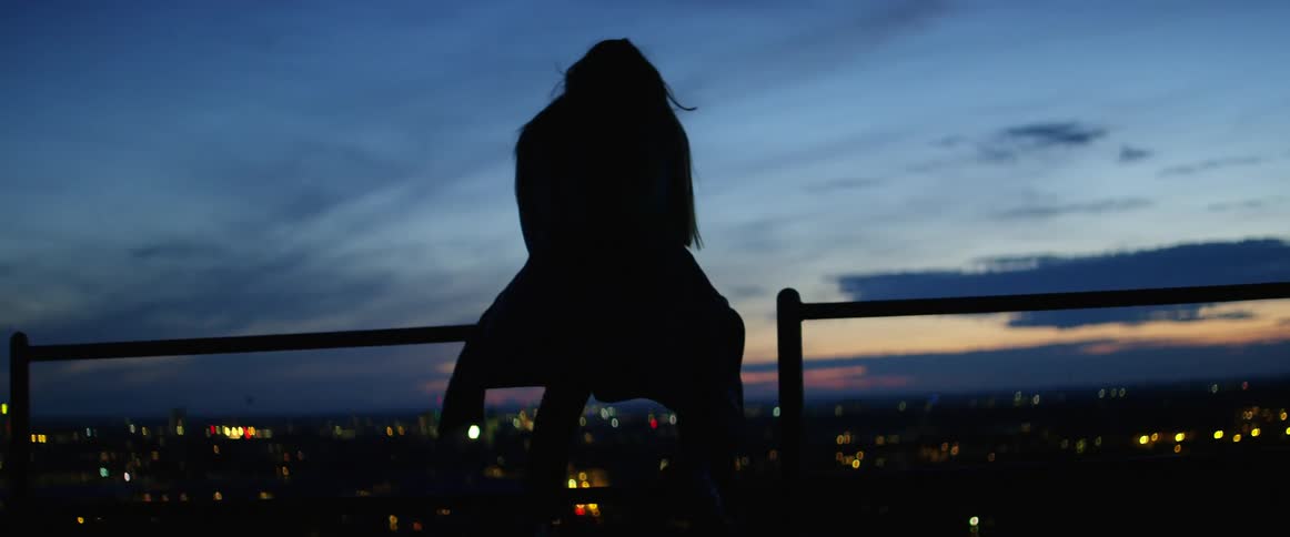 The woman sits near the fence
