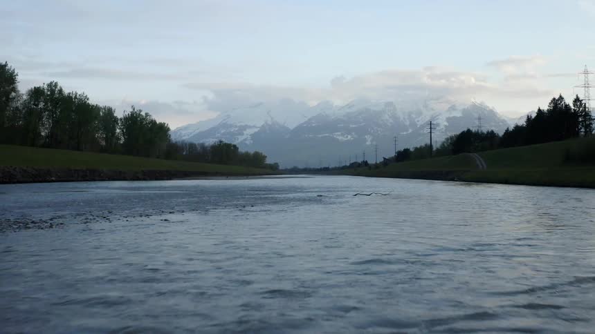 River flows along path toward snow capped mountain on the horizon