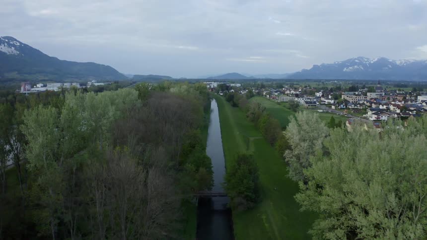 A stream of water flows next to trees and a town