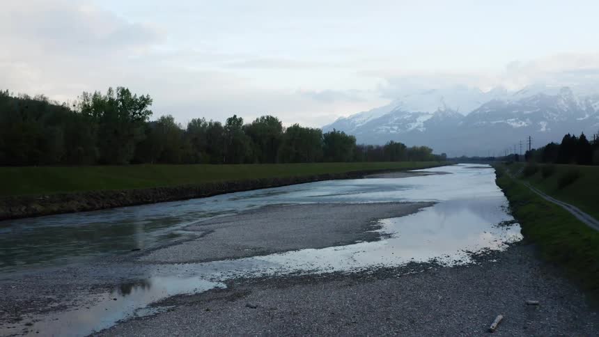 An aerial view of a dried up river with snowy mountains in the distance