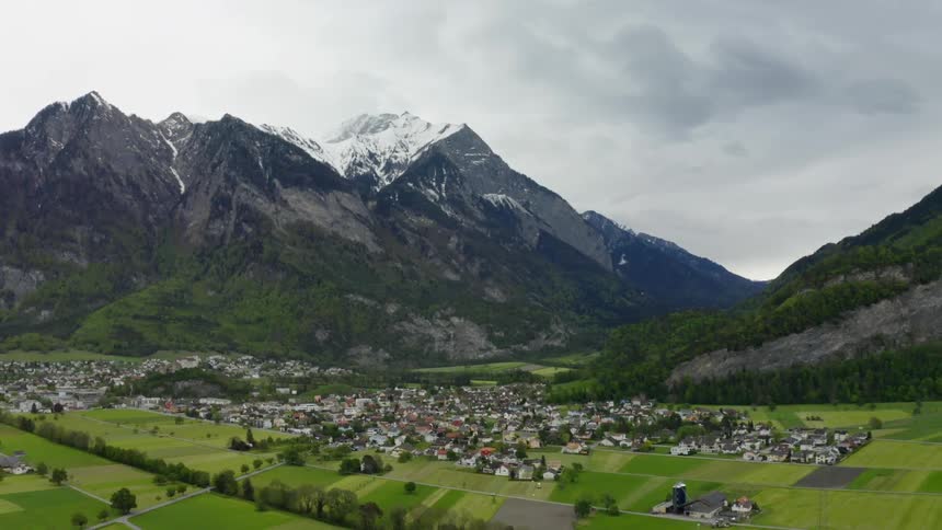 Aerial view of a small town situated in a valley and mountains in the background