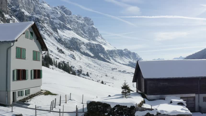 Houses covered in snow with mountains and the sky in the background