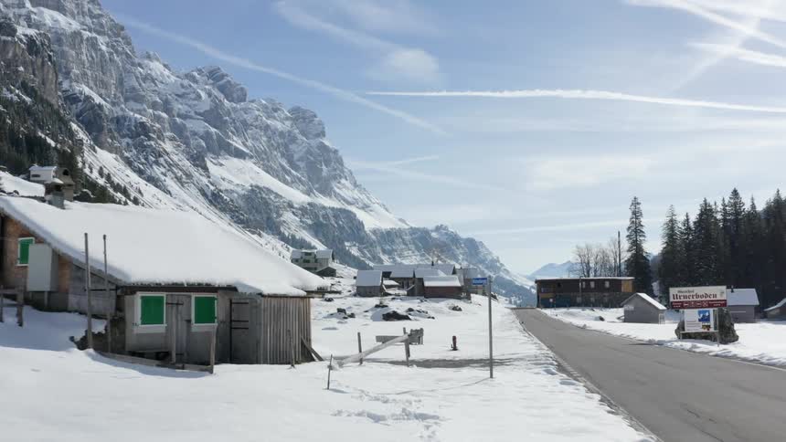 A road through a small snow covered town at the base of a mountain
