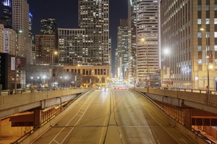 Headlights blur as cars travel on and off a city highway ramp at night