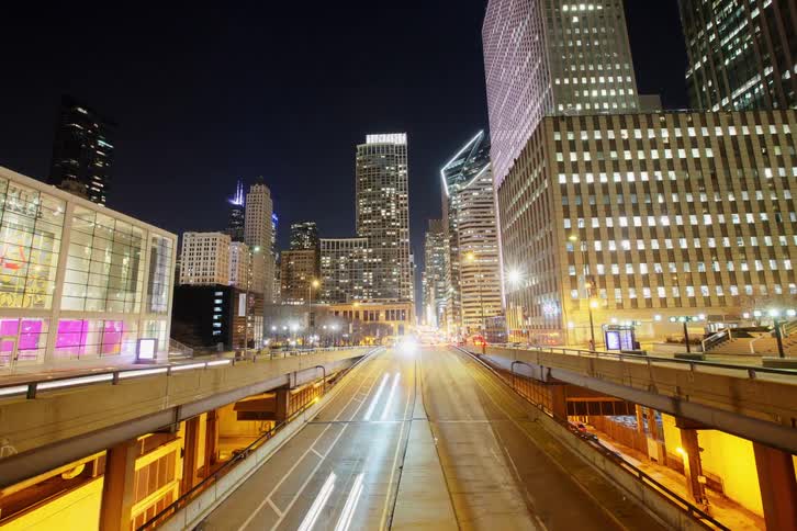 Traffic and people move through a downtown part of the city at night