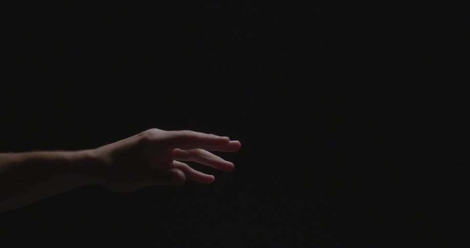 A hand moves in front of a black background