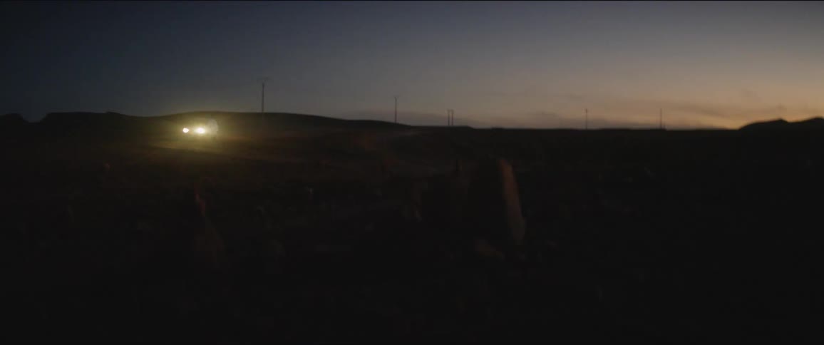 A car with headlights on navigates a road out in the middle of a nowhere