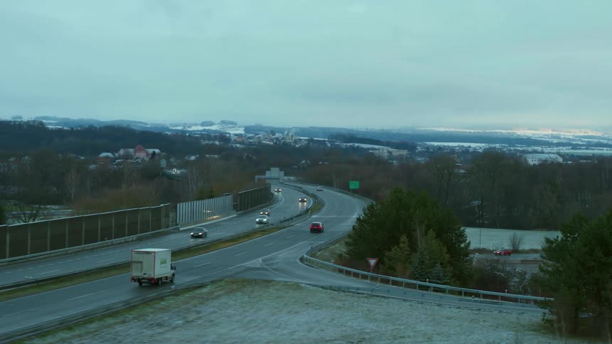 Traffic moves down a roadway toward a small town in the distance